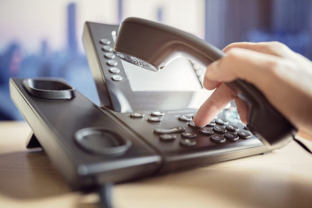 Person Dialing A Call On A Business Phone System.